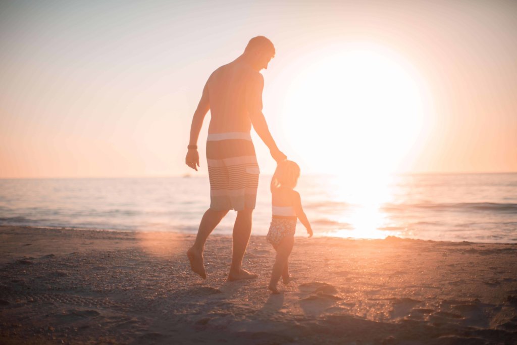 A father and child on the beach at sunset