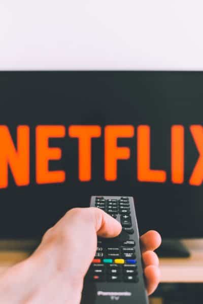 hand with remote pointing at television with Netflix