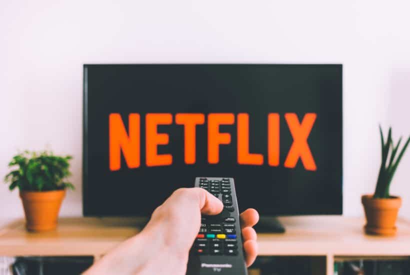 hand with remote pointing at television with Netflix