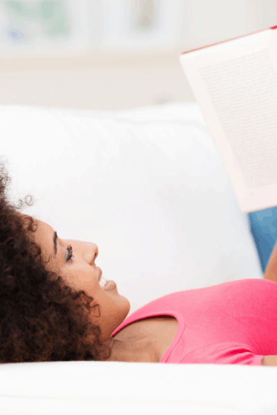 woman laying on couch reading book