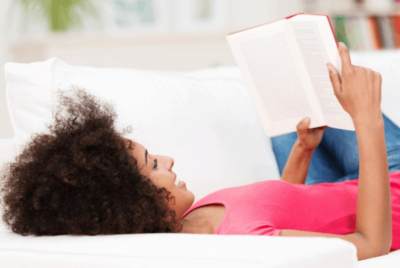 woman laying on couch reading book