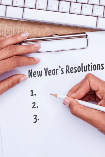 wooden desk with close up of someone writing new year's resolutions