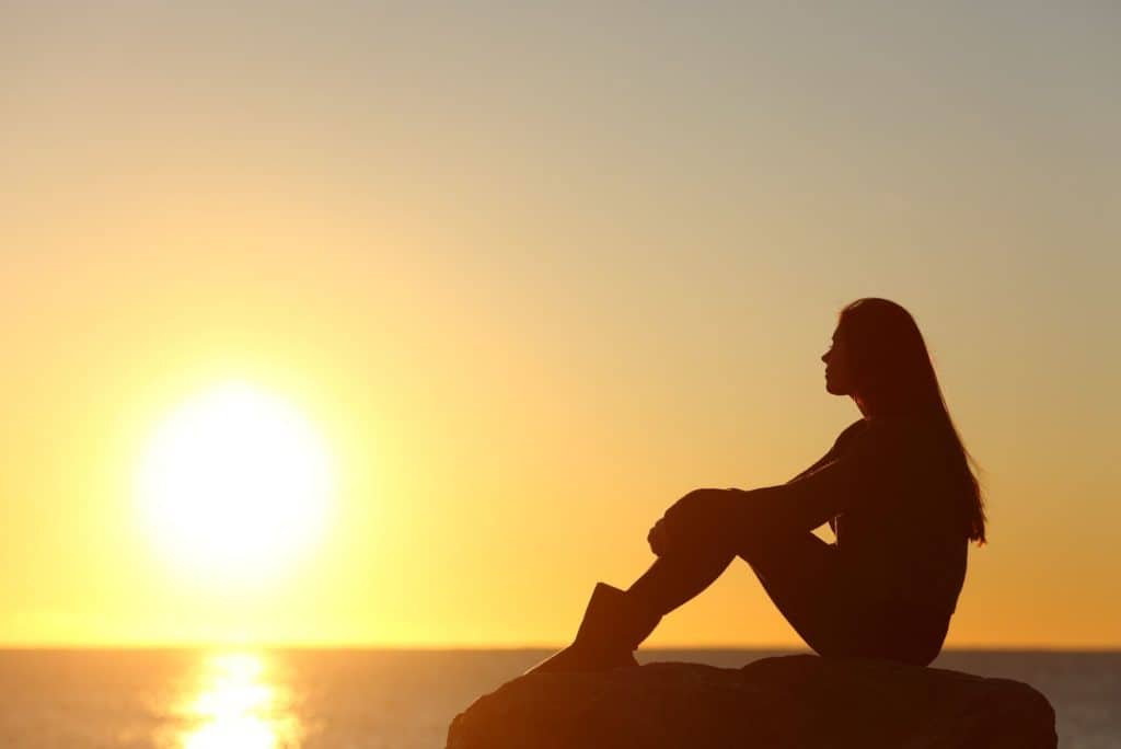 silhouette of woman facing sunset