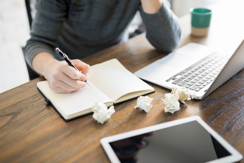 woman writing at desk with laptop and tablet