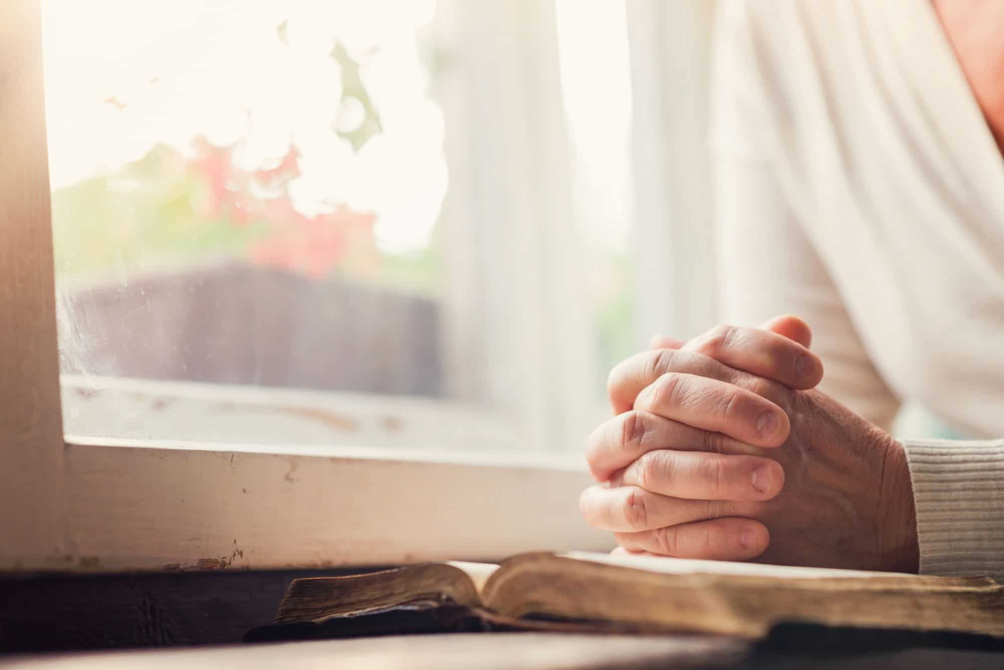 woman with open bible pray at window